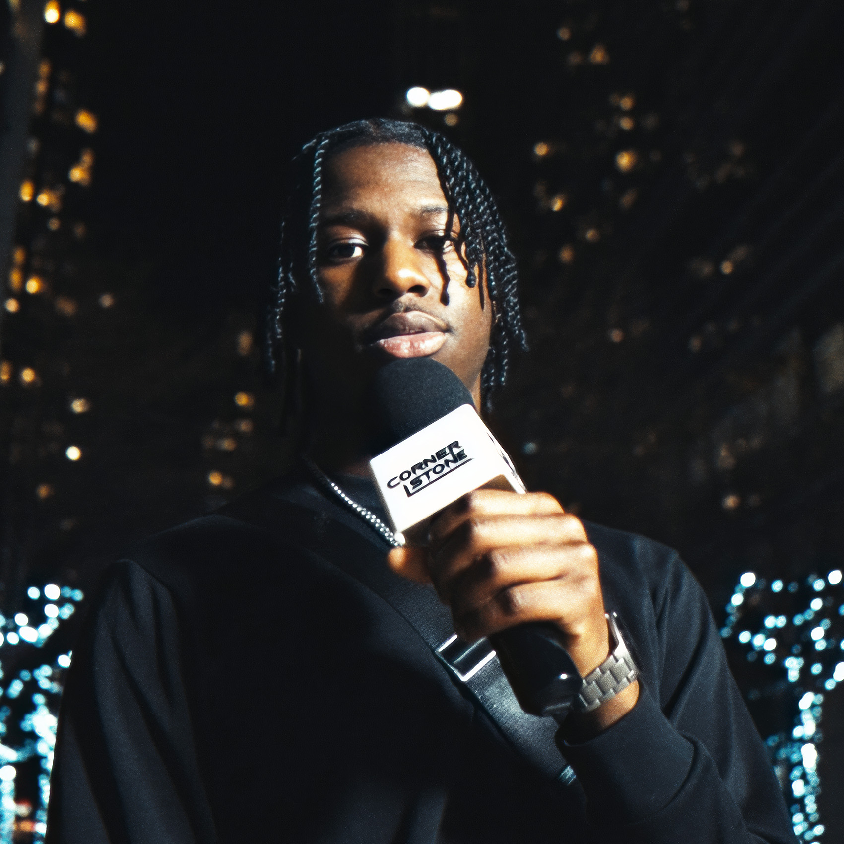 Artist holding a Cornerstone microphone at night with city lights behind
